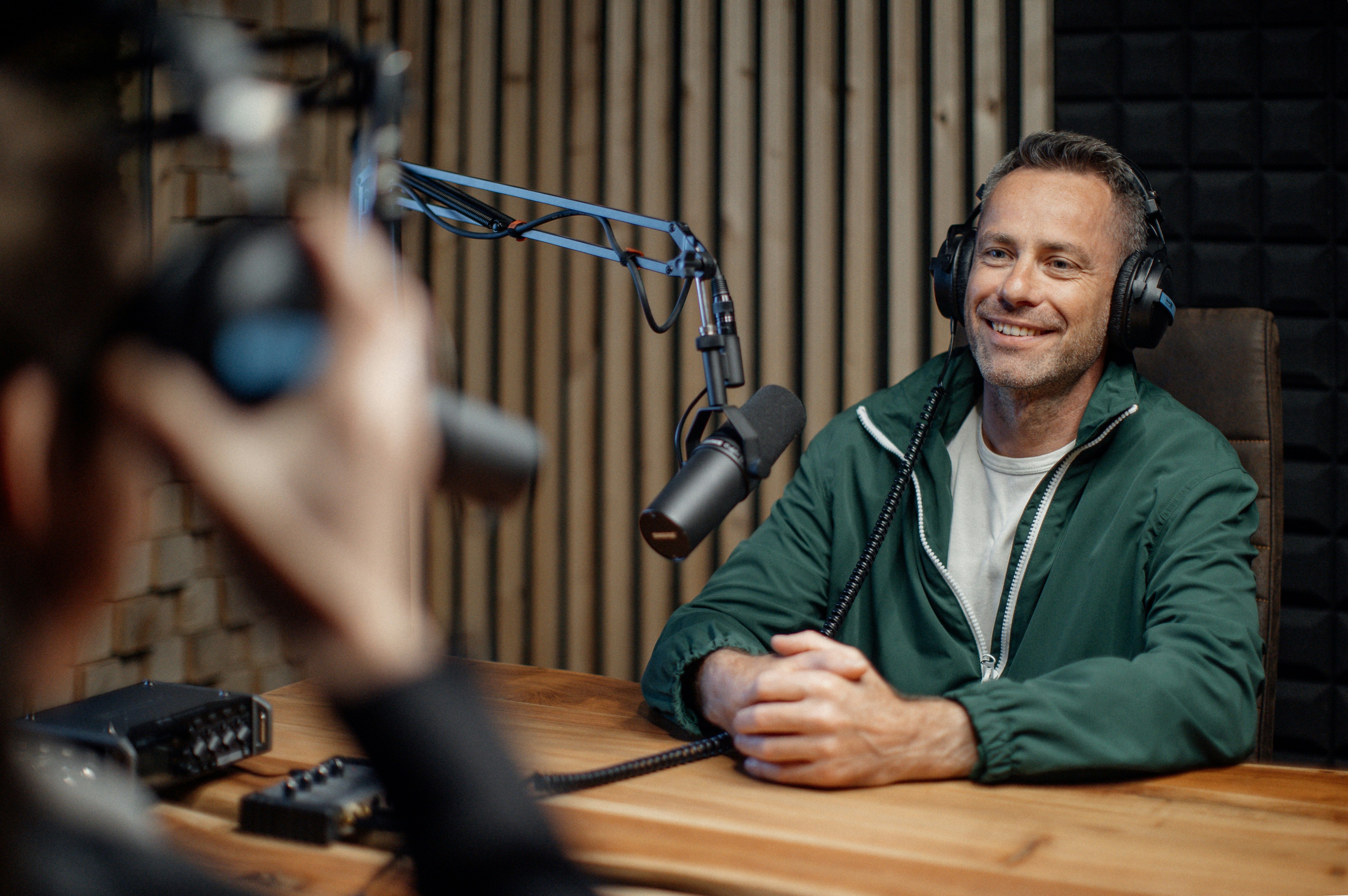 Man met koptelefoon in professionele podcaststudio achter microfoon