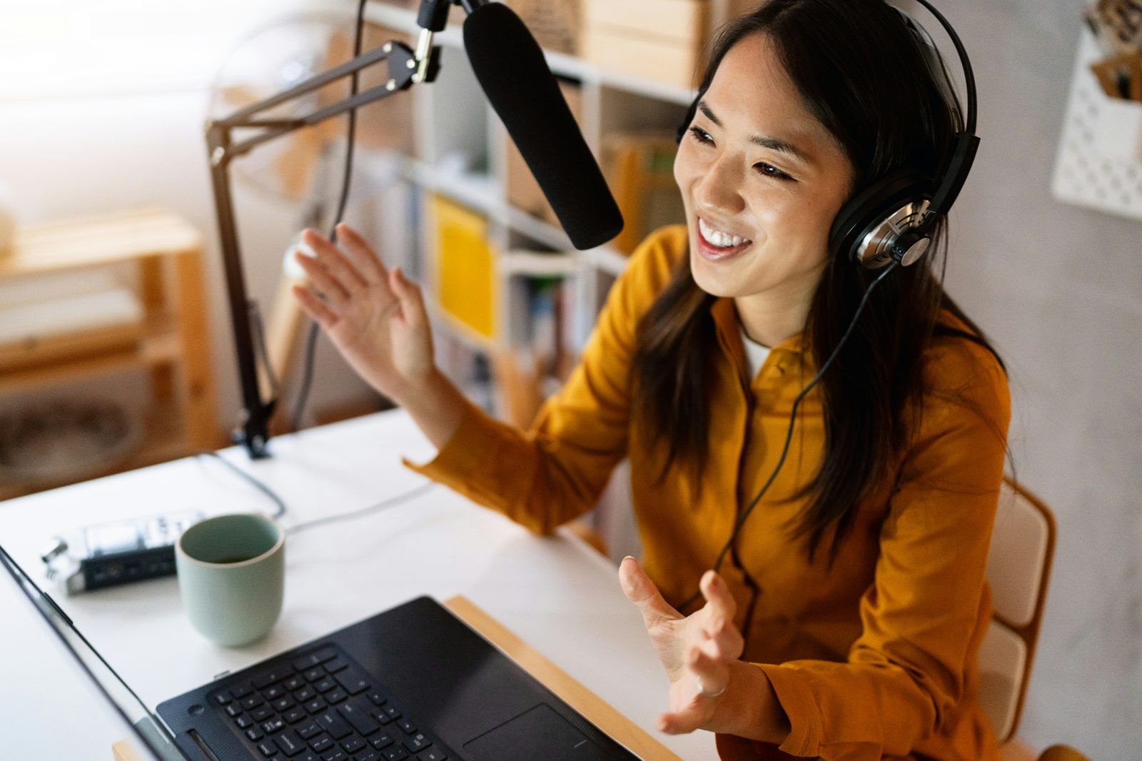 Vrouw met koptelefoon neemt enthousiast podcast op in home studio