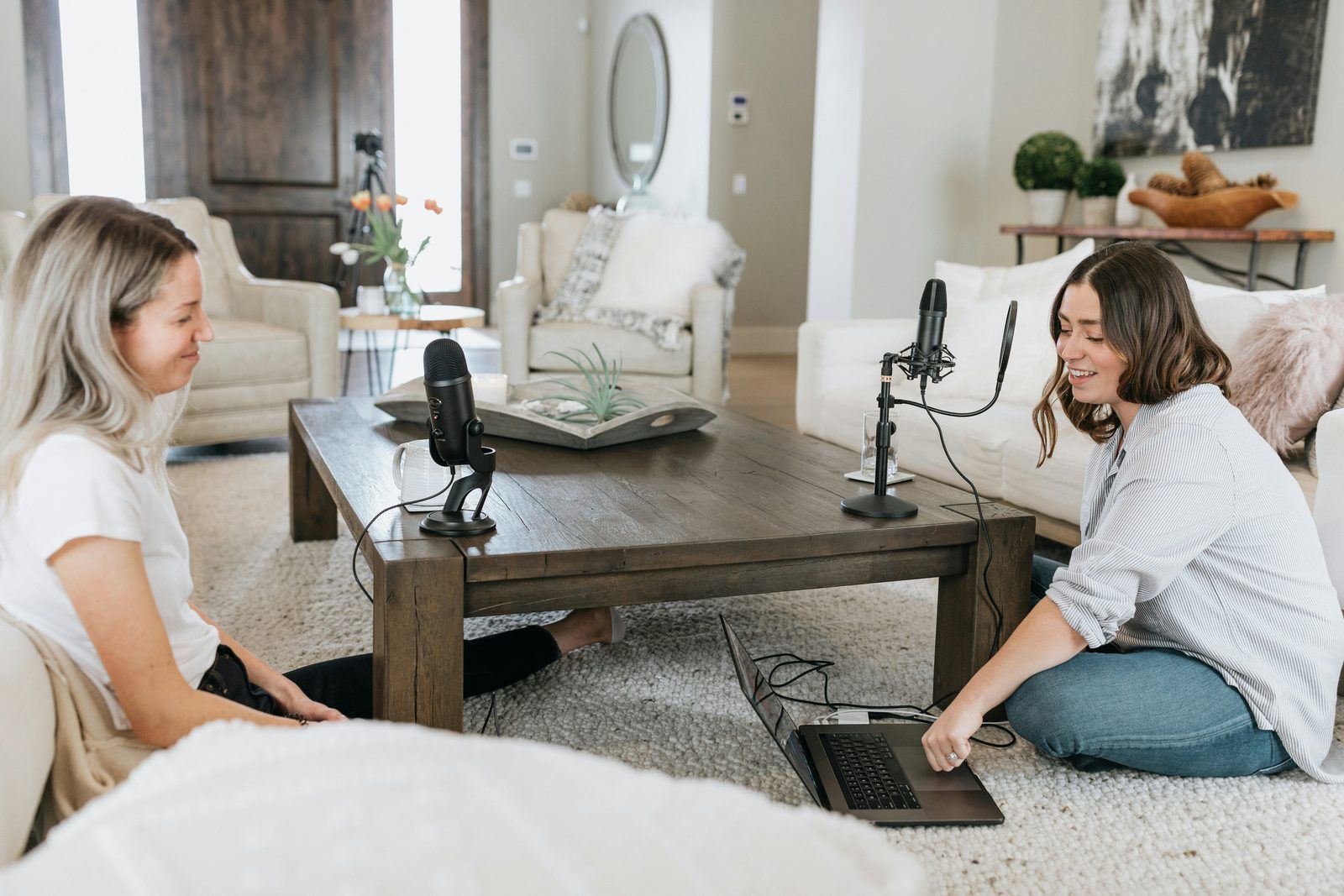 Twee vrouwen nemen podcast op in lichte woonkamer met microfoons