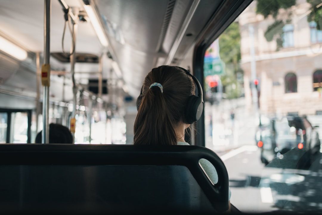 Vrouw met koptelefoon in de bus, podcast luisteren onderweg